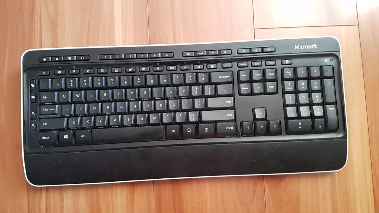 Clavier noir Microsoft avec pavé numérique sur une surface en bois