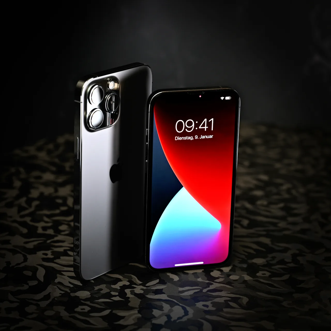 Deux iPhone photographiés de face et de dos sur un fond sombre