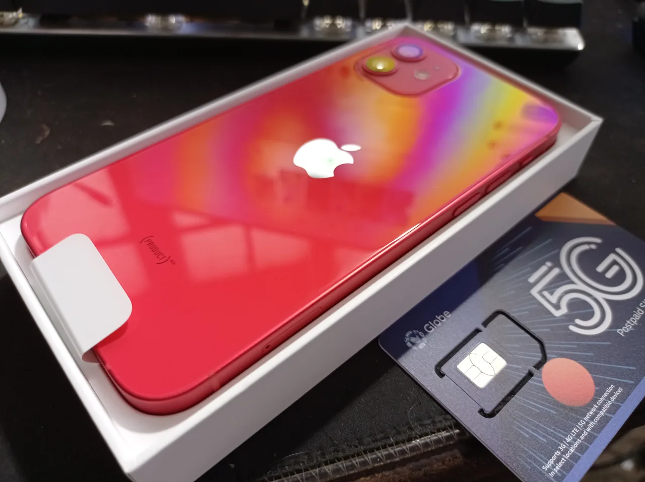 iPhone 12 rouge photographié de dos sur une boîte