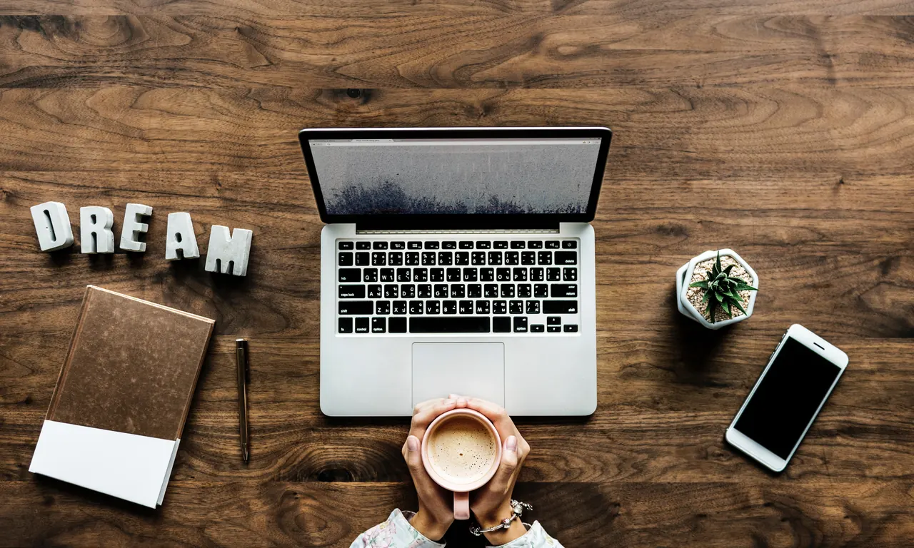 MacBook sur un bureau vu du dessus, avec smartphone et tasse