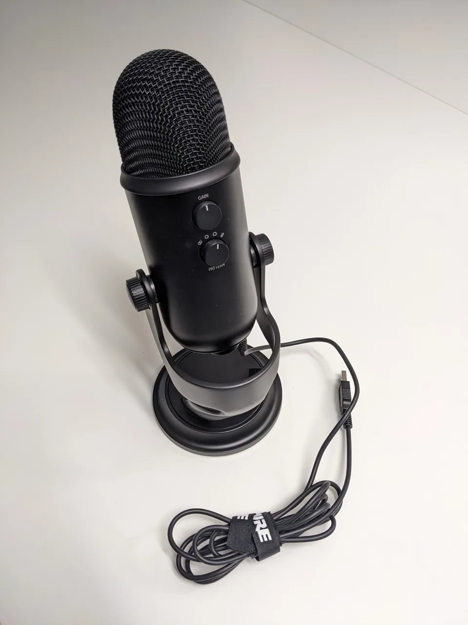Microphone Blue Yeti noir posé sur un bureau avec son câble USB